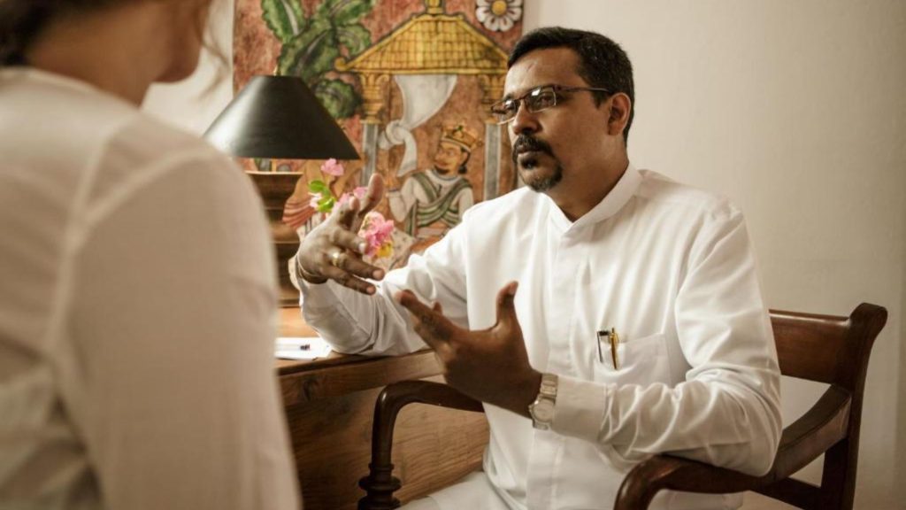 Dr. Upul bei der Pulsdiagnose im Behandlungsraum des Thaulle Resorts