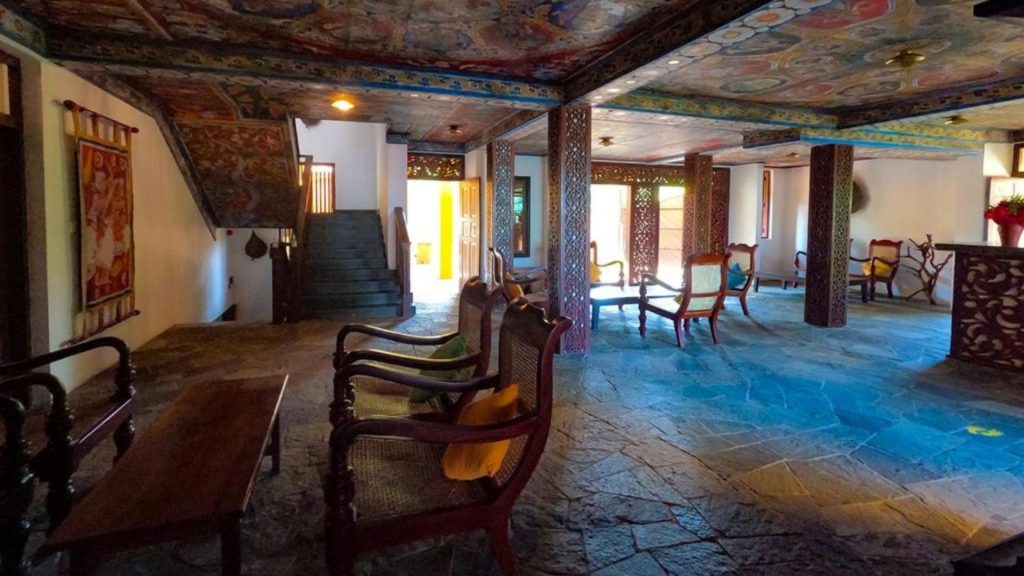 Großzügiger Innenraum mit Natursteinboden, Holzmöbeln und kunstvoller Decke