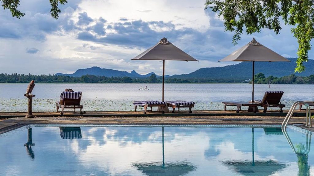 Infinity-Pool mit Sonnenschirmen und freiem Blick auf den See in Sri Lanka