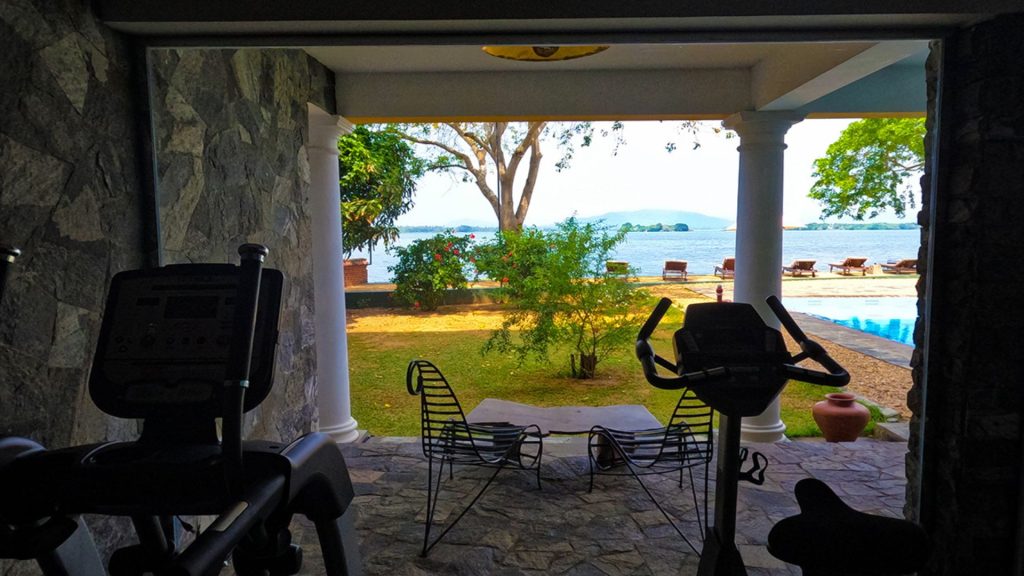 Offener Fitnessbereich mit Blick auf Garten, Pool und See