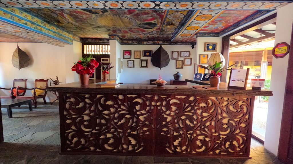 Rezeption im Thaulle Resort mit geschnitztem Empfangstresen und dekorativer Holzdecke