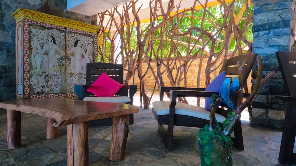 Sitzbereich im Freien mit Holzmöbeln, bunten Kissen und dekorativer Aststruktur