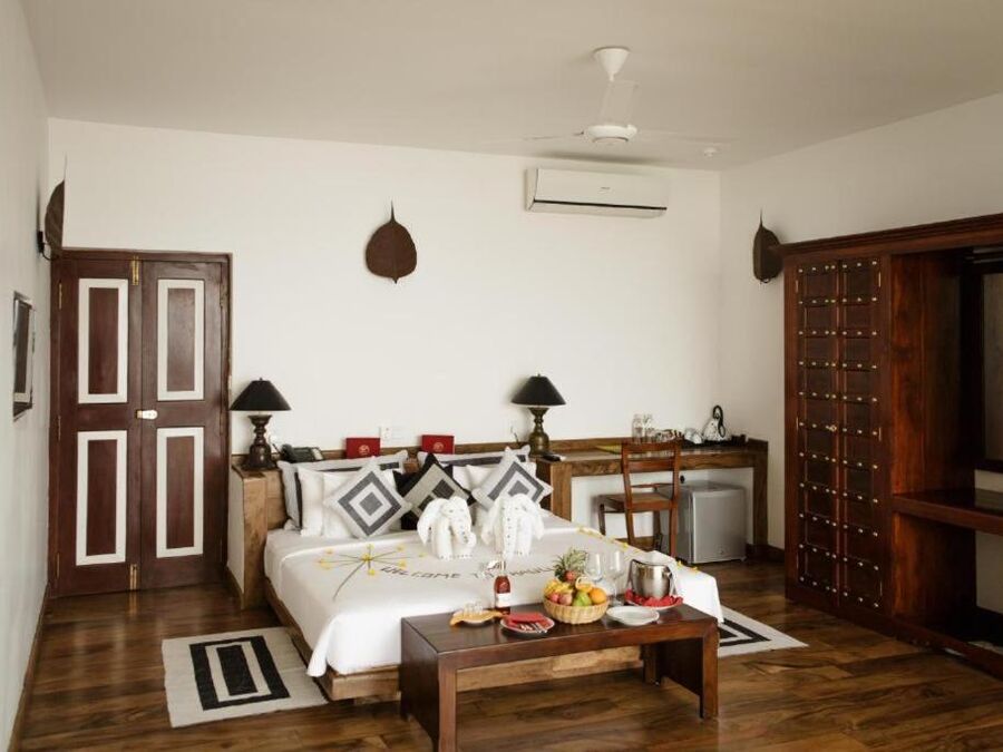 Großzügiges Classic-Deluxe-Zimmer mit Bett, Sitzgelegenheit und Holztüren