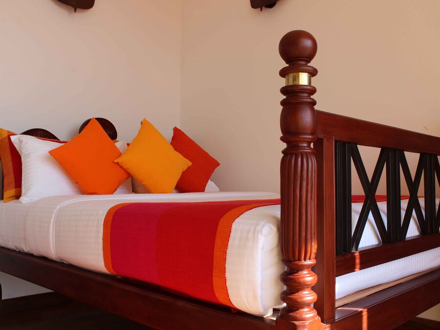 Standardzimmer mit Doppelbett, orange-roter Tagesdecke und Fensterfront