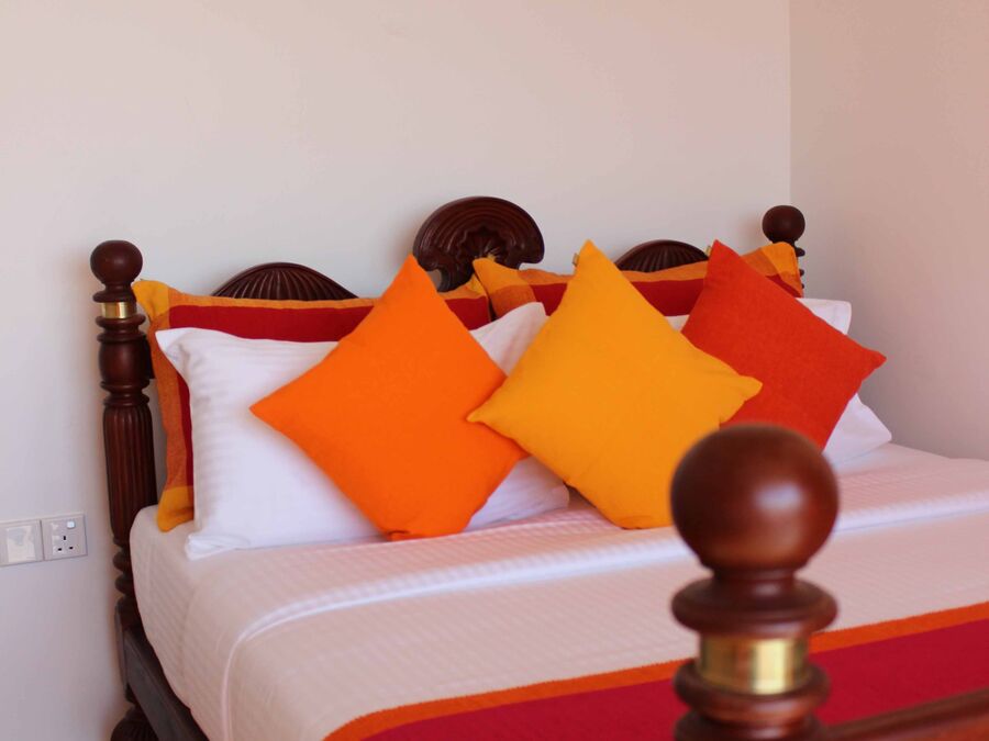 Bett im Standardzimmer mit farbigen Kissen vor heller Wand