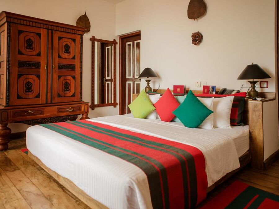 Superior-Zimmer mit Kingsize-Bett, bunten Kissen und antikem Holzschrank